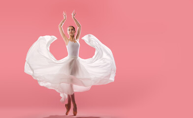 elegant ballerina in pointe shoes dancing in a long white skirt on a pink background