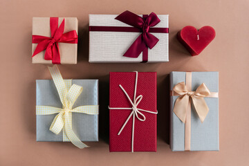 Gift boxes and red candle in a shape of heart on craft paper background. Valentines day concept. Top view, flat lay
