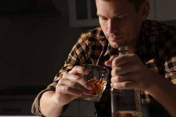 Addicted man with alcoholic drink in kitchen, closeup
