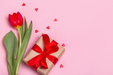 Craft gift box with a red ribbon, flowers and a paper hearts on a pink background for Valentine's Day. Mother's Day.