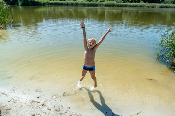 a boy bathes in a forest lake, jumps, in the water