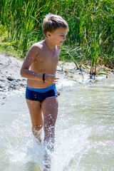 a boy bathes in a forest lake, jumps, in the water