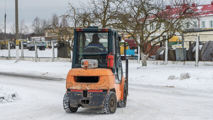 The forklift truck on the winter street. Outdoor forklift transporting cargo on the openair warehouse.