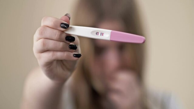 Teenage girl shows a strip test for pregnancy. Two lines, positive result. Teenage pregnancy.
