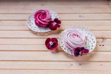 Beautiful delicious dessert. Pink zephyr on wooden background and pink flowers.Plate with Berry,Meringue zephyr dessert.