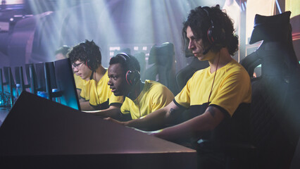 Angry esportsman gamer player breaking keyboard and touching head while expressing disappointment sitting near teammates after loss in professional video game match © Framestock
