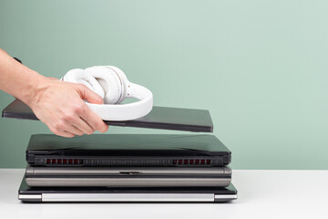 Woman hands put laptop computer and headphones on pile of old used laptop computers for recycling...