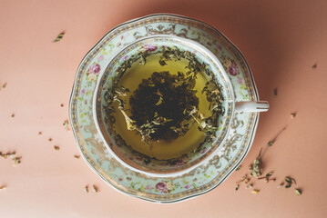 turquoise cup with flowers with green tea on a pink background