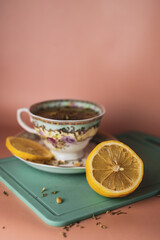 turquoise cup with flowers with green tea with lemon on a blue cutting board on a pink background