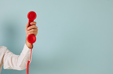 Man hand isolated on green studio background hold corded telephone for call center service ad. Male with wired phone express communication, make call for feedback or opinion. Copy space. - obrazy, fototapety, plakaty