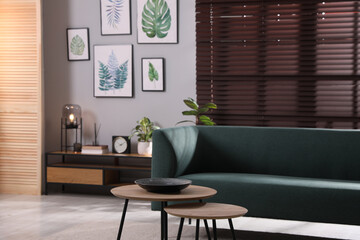 Fototapeta na wymiar Stylish living room interior with comfortable sofa and small tables