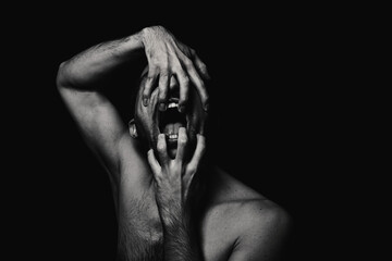 Male portrait in horror style. Black-white male portrait on a black background. Man opens his jaw...