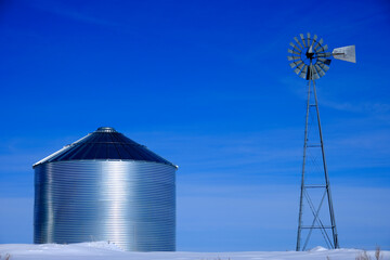Windmill and Grain Silos in Winter Snow on Farm for Agricultural Farming