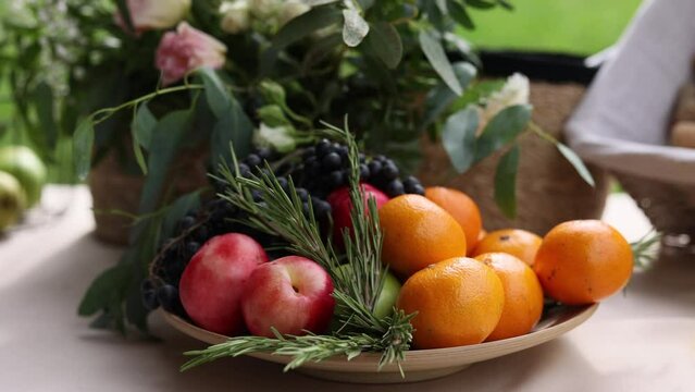 A fruit plate. Various fruits with rosemary on the table. Black grapes, nectarines, tangerines and green apples. 