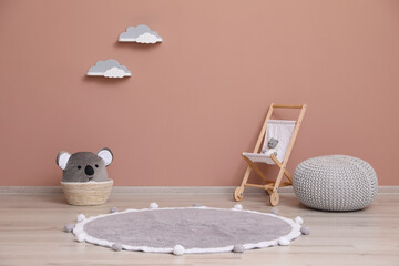 Wicker basket, toys and pouf near pink wall indoors. Interior design
