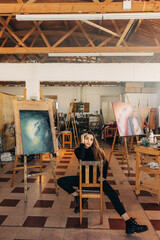 Confident female artist sitting in her workshop