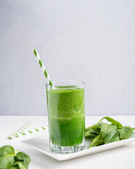 Green homemade vegetarian smoothie or juice made of spinach leaves which are source of vitamins and...