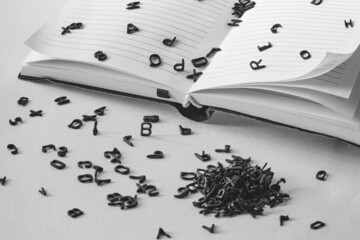 letters of the alphabet fall out of the notebook, black and white shot, concept or idea of ​​a...