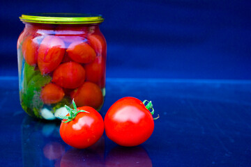 Two red tomatoes against a background of pickled tomatoes. 