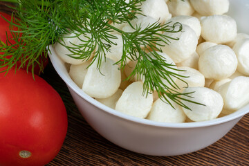 Piece of mozzarella Buffalo in white bowl and tomatoes. Decorated with dill