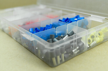 A set of colored crimp terminals for electrical wires. Crimping sleeves of different sizes. Plastic spare parts box for electrician. Toolbox. Selective focus