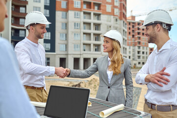 Friendly young builder shaking hands with a pleased woman supervisor