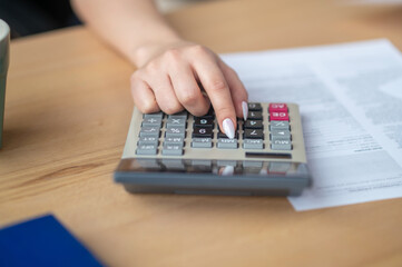 Bookkeeper seated at the office desk using a pocket calculator