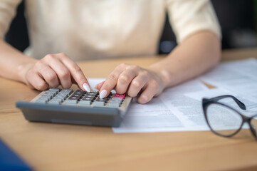Experienced accountant making financial calculations on the calculating device