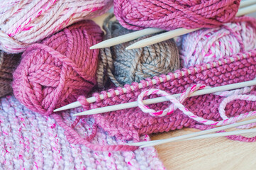 Skeins of thread and knitting needles on wooden background, selective focus.	