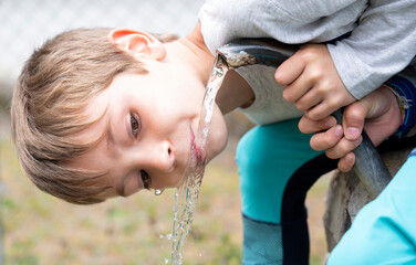 child drinking water from a fountain