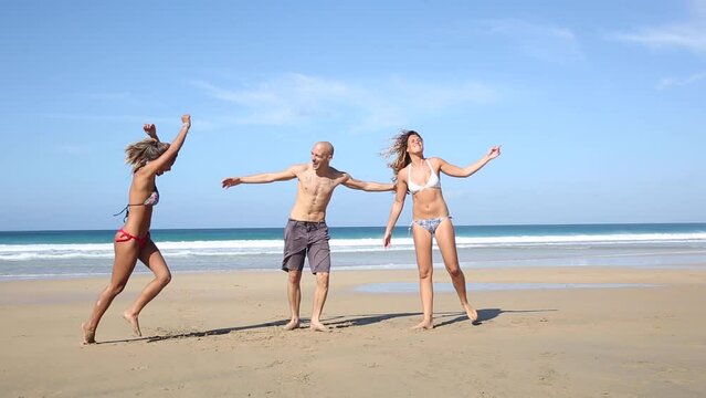 Multiracial group of friends jumping on the beach and celebrating success at seaside