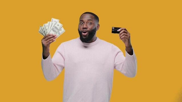 African American man shows cash or credit card. money banknotes and card, african american man guy with success in cash financial freedom on yellow background