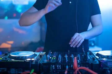 Close up Front view of of DJ hands controlling a music table in a night club. High quality photo