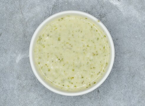 Raita with mint, herbs and onion in a bowl top view on dark grey background indian pakistani food