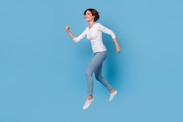 Full size profile side photo of excited cheerful girl traveling on weekend running isolated on blue color background