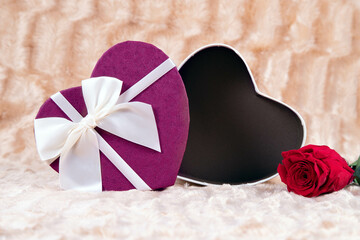
Open box to include a heart-shaped gift with a clear bow, accompanied by a red rose on a background of golden waters