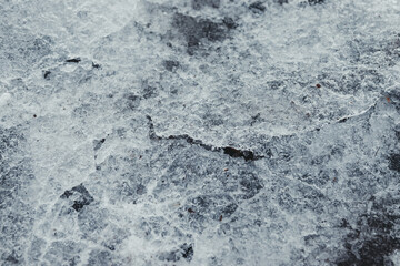Cracked ice on concrete with yellow leaves. Yellow leaves and concrete can be seen under the cracked ice