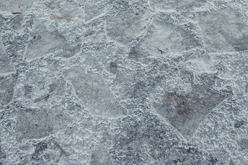 Cracked ice on concrete with yellow leaves. Yellow leaves and co