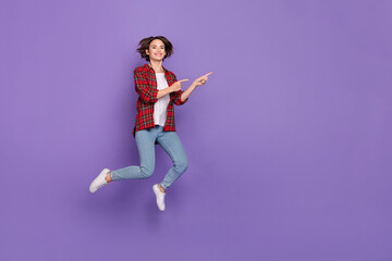 Fototapeta na wymiar Full length photo of funny young brunette lady jump index promo wear shirt jeans sneakers isolated on purple background