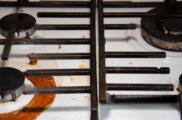 Dirty gas stove in kitchen with copy space. White surface of stove in dried burnt spots of fat with gas burner. Concept of careless use of household appliances.