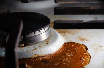 Dirty gas stove in kitchen with copy space. White surface of stove in dried burnt spots of fat with gas burner. Concept of careless use of household appliances.