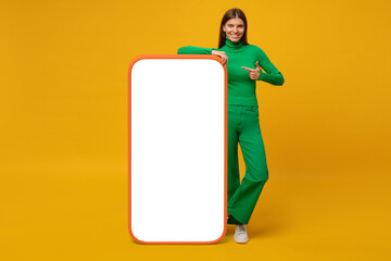 Young woman standing and showing with finger blank screen of huge phone, mockup for your app
