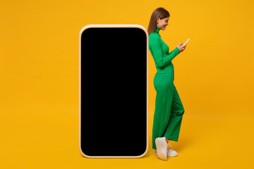 Young woman standing and leaning on huge phone mock up for app