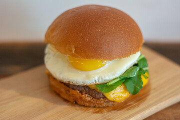 Cheeseburger with bread, fried egg, arugula, cheese and patty.