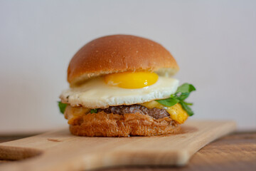 Cheeseburger with bread, fried egg, arugula, cheese and patty.