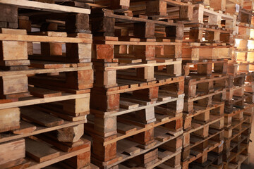 Many empty wooden pallets stacked in warehouse