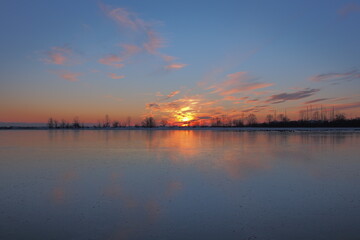 Fototapeta na wymiar Winter sunset reflecting off frozen water 