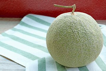 A Fresh Ripe Muskmelon or Cantaloupe Melon Fruit Isolated on Striped Dish Towel