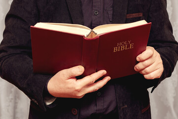 A man holds an open Bible in his hands. Reading and studying the Bible