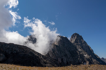 Clouds accumulating around the sharp mountain peaks of the Chaukhi massif in the Greater Caucasus Mountain Range in Georgia, Kazbegi Region. Mountain Ridges, Hiking. Georgian Dolomites. Cloudscape